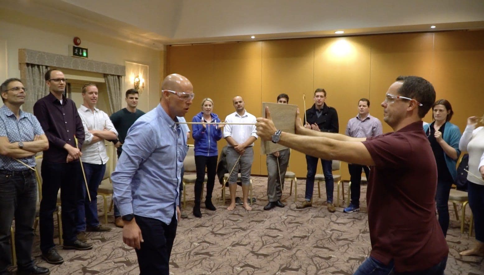 A group watching as a participant breaks an arrow in an empowerment exercise