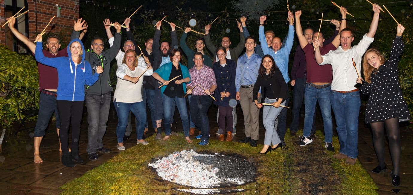 A group cheering with their arms in the air beside a bed of embers after a fire walk