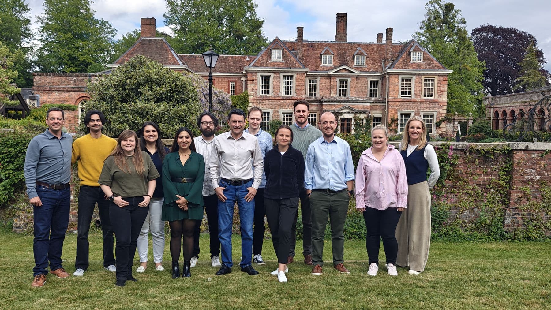 A team standing together on the lawn of a country house during an offsite