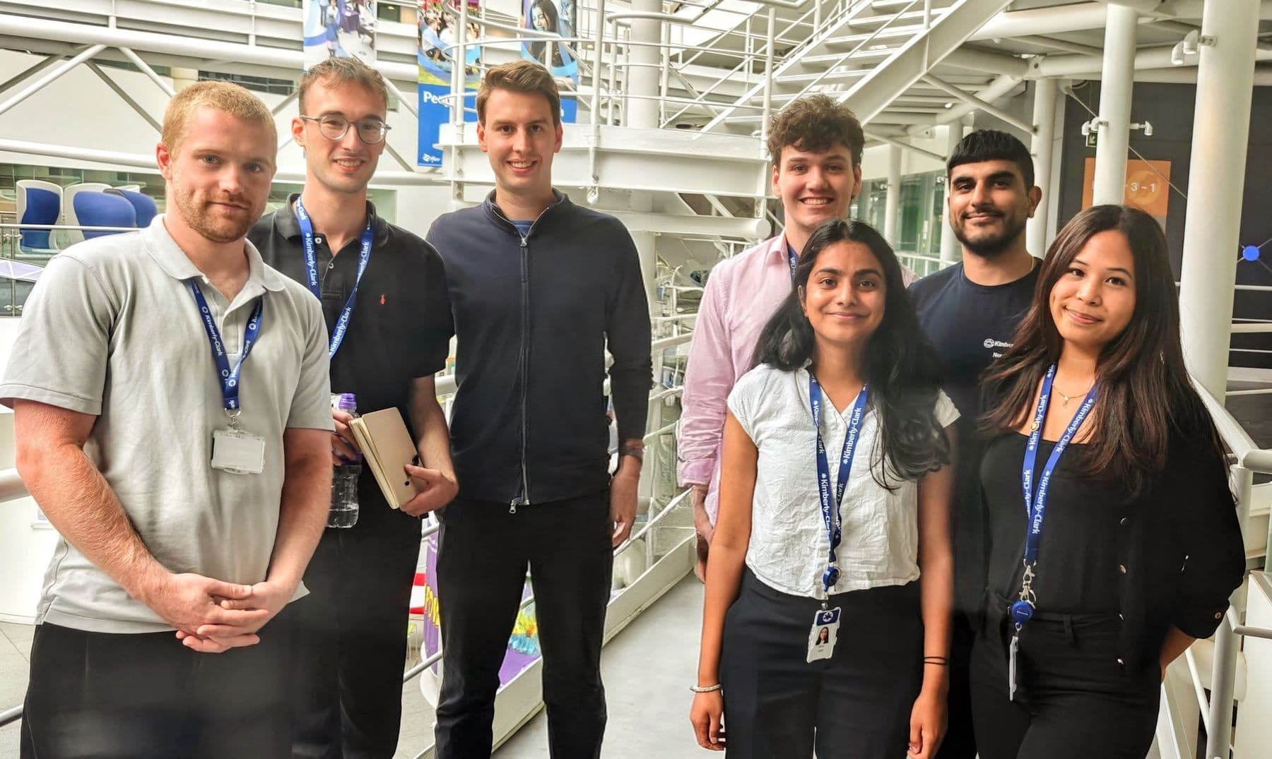 A group of graduates standing together in their company's atrium
